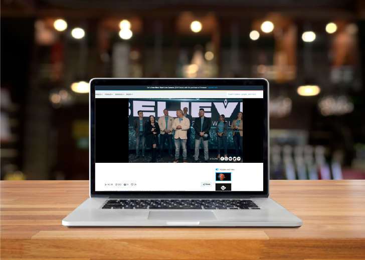 MacBook laptop showing feed of livestream event on counter in coffeeshop